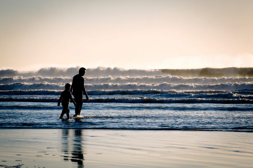 A man walking on a beach with son